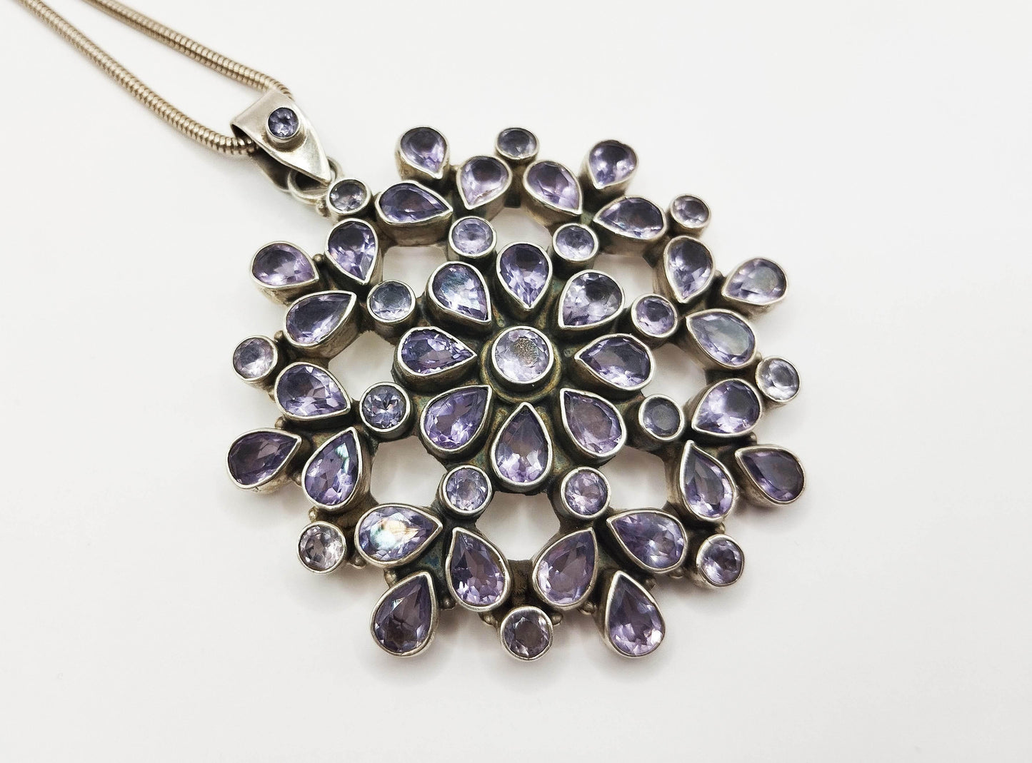 Ασημένιο κολιέ με μεγάλο μενταγιόν σε σχήμα λουλουδιού στολισμένο με αμέθυστο.
Εντυπωσιακό κομμάτι με 51 ασημένια καστόνια που περικλείουν τις πέτρες αμέθυστου.