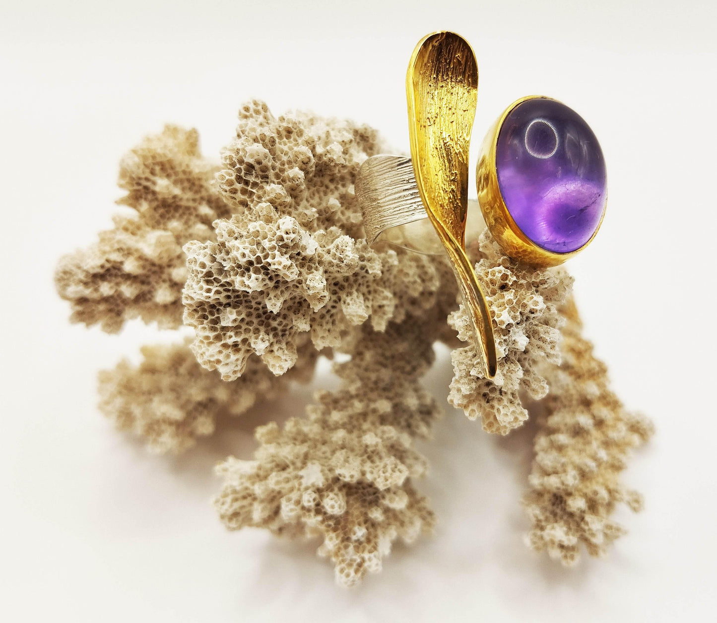 Αυτό το εντυπωσιακό δαχτυλίδι έχει μια οβάλ πέτρα από αμέθυστο και ένα επίχρυσο "φύλλο" πάνω σε ασημένια βάση.
Η τραχιά επιφάνεια του "φύλλου" κάνει το κόσμημα να φαίνεται πιο "φυσικό" και αναδεικνύει την τέχνη της κατασκευής του.
Είναι φτιαγμένο από επίχρυσο ασήμι 18Κ και το μέγεθος είναι ρυθμιζόμενο.