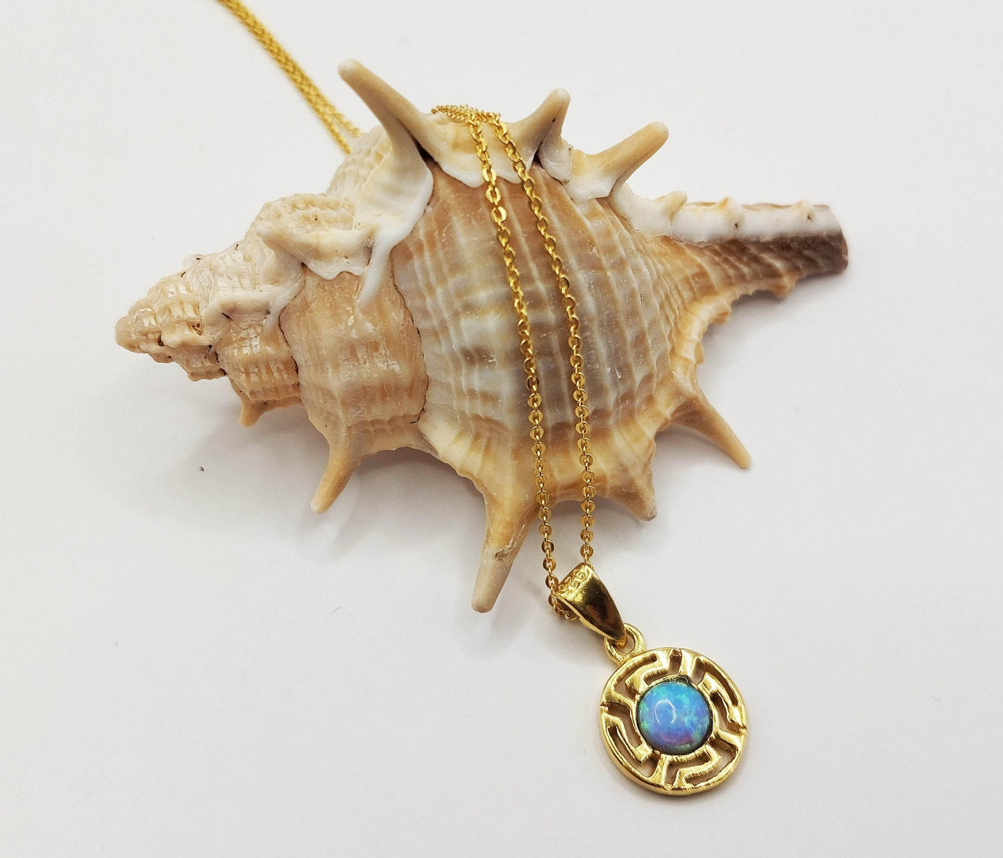 Κολιέ από επιχρυσωμένο ασήμι με επίχρυσο μενταγιόν. Το μενταγιόν έχει γαλάζιο οπάλιο στο κέντρο του και σχέδιο μαιάνδρου γύρω γύρω.