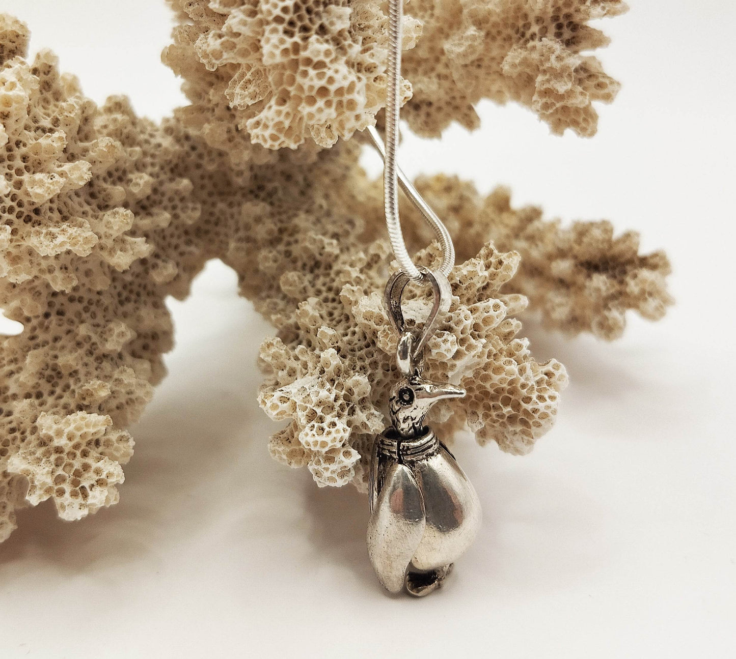 Ασημένιο κολιέ με ασημένιο μενταγιόν σε σχήμα πιγκουίνου.
Το κεφάλι, τα φτερά και τα πόδια του πιγκουίνου είναι κινούμενα.