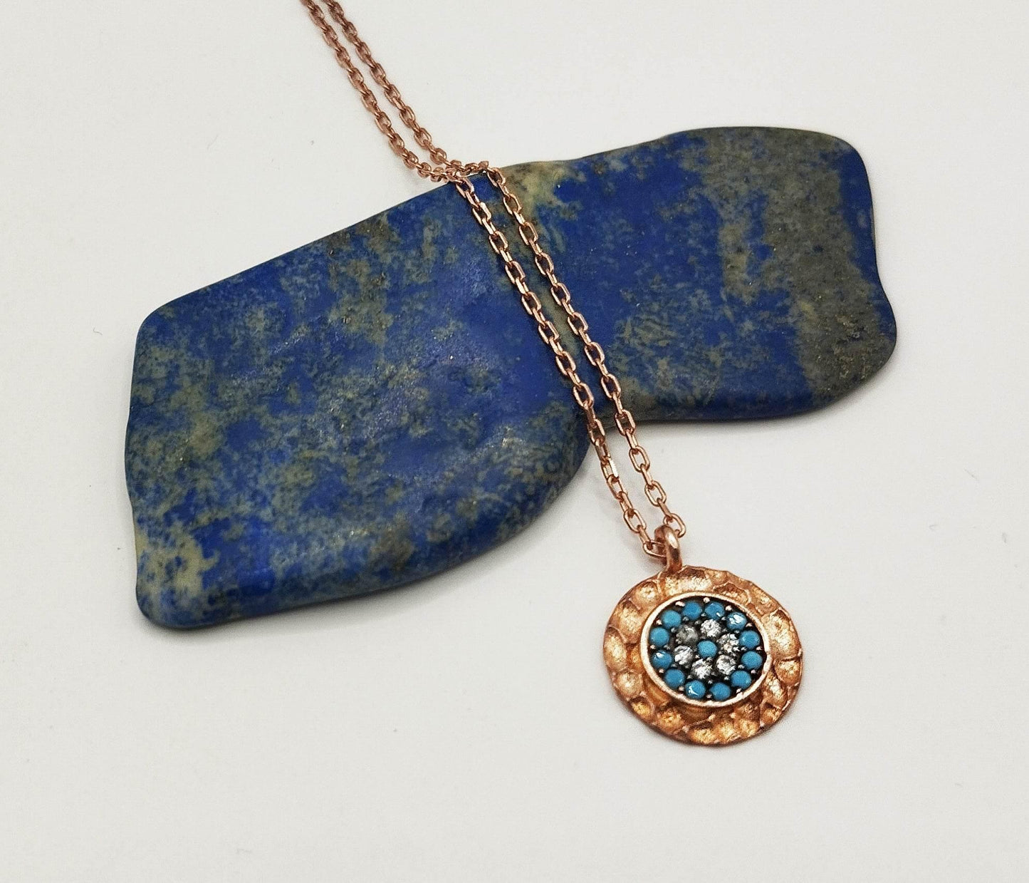 Κολιέ από ροζ επιχρυσωμένο ασήμι με στρογγυλό μενταγιόν με γαλάζια και λευκά ζιργκόν.