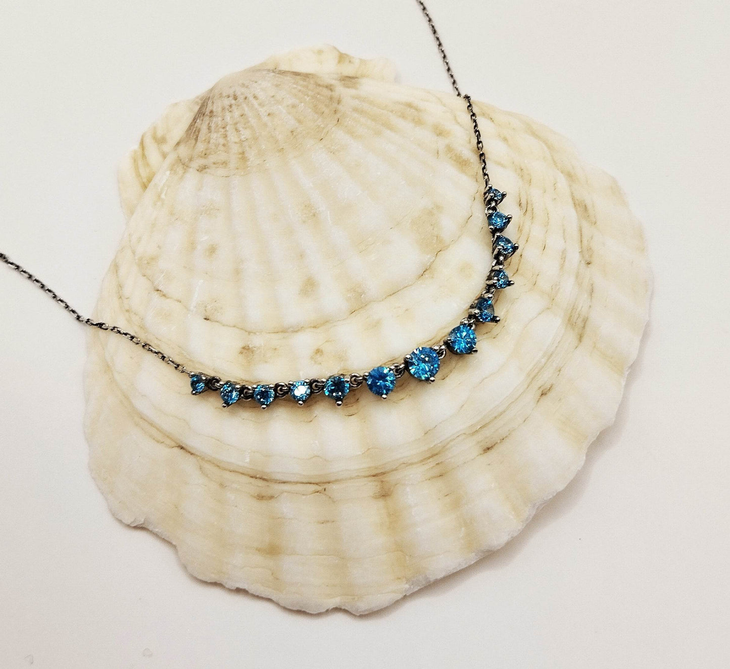 Ασημένιο κολιέ με μια σειρά από γαλάζιες πέτρες ζιργκόν.
