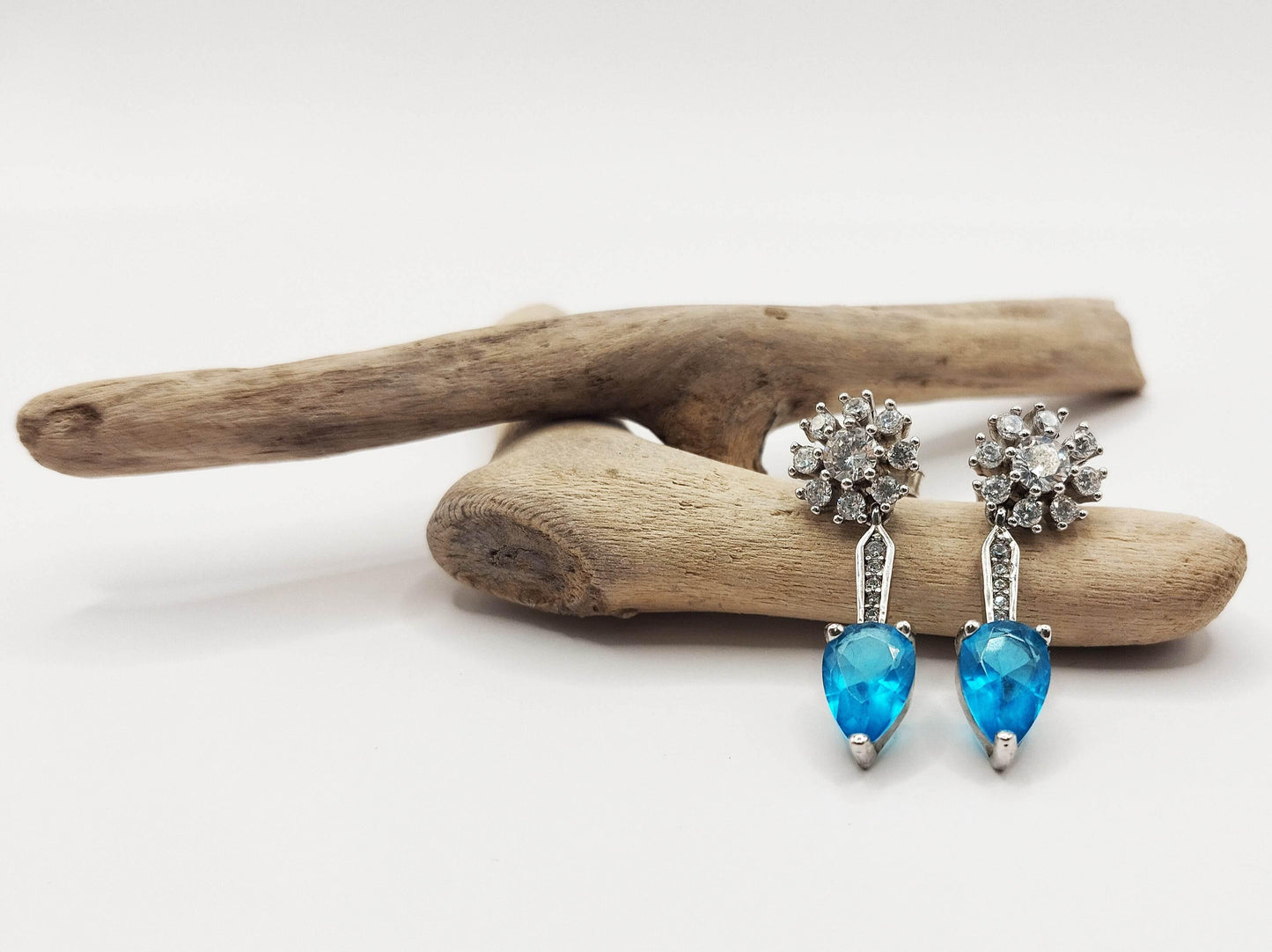 Ασημένια σκουλαρίκια με γαλάζια πέτρα ζιργκόν και λευκά "λουλούδια" από ζιργκόν.
Τέλεια για λαμπερές βραδινές εξόδους.